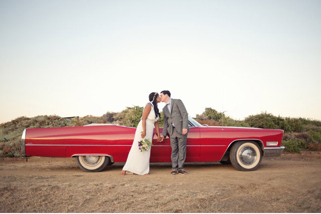 bride and groom with red car