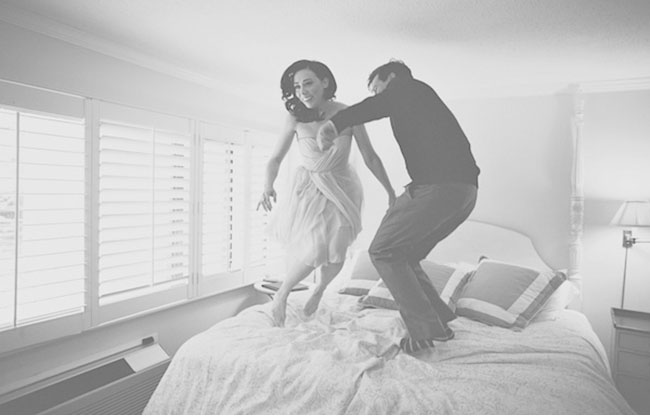bride and groom jumping on bed