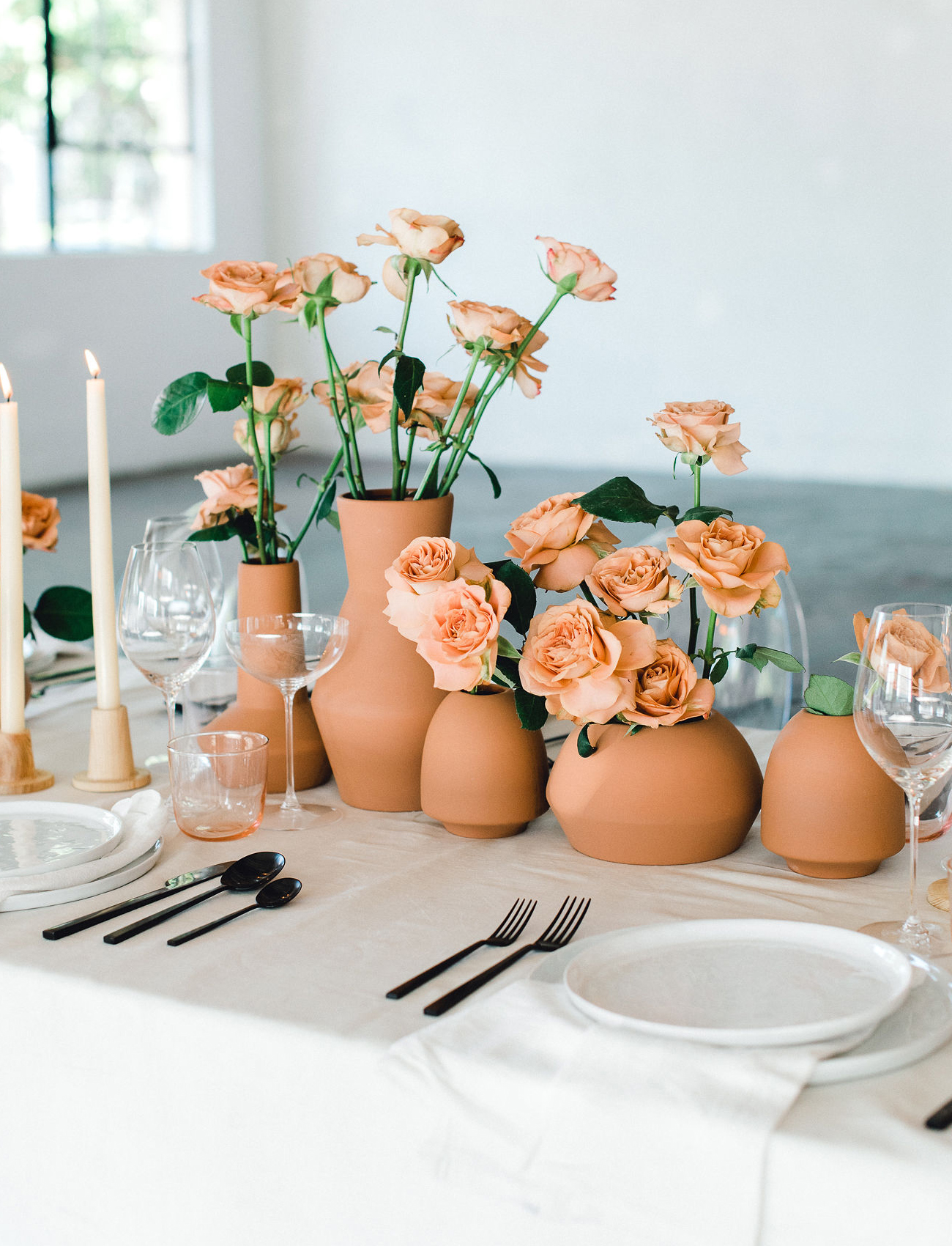Mono-floral centerpiece of terracotta vases with rust tone roses