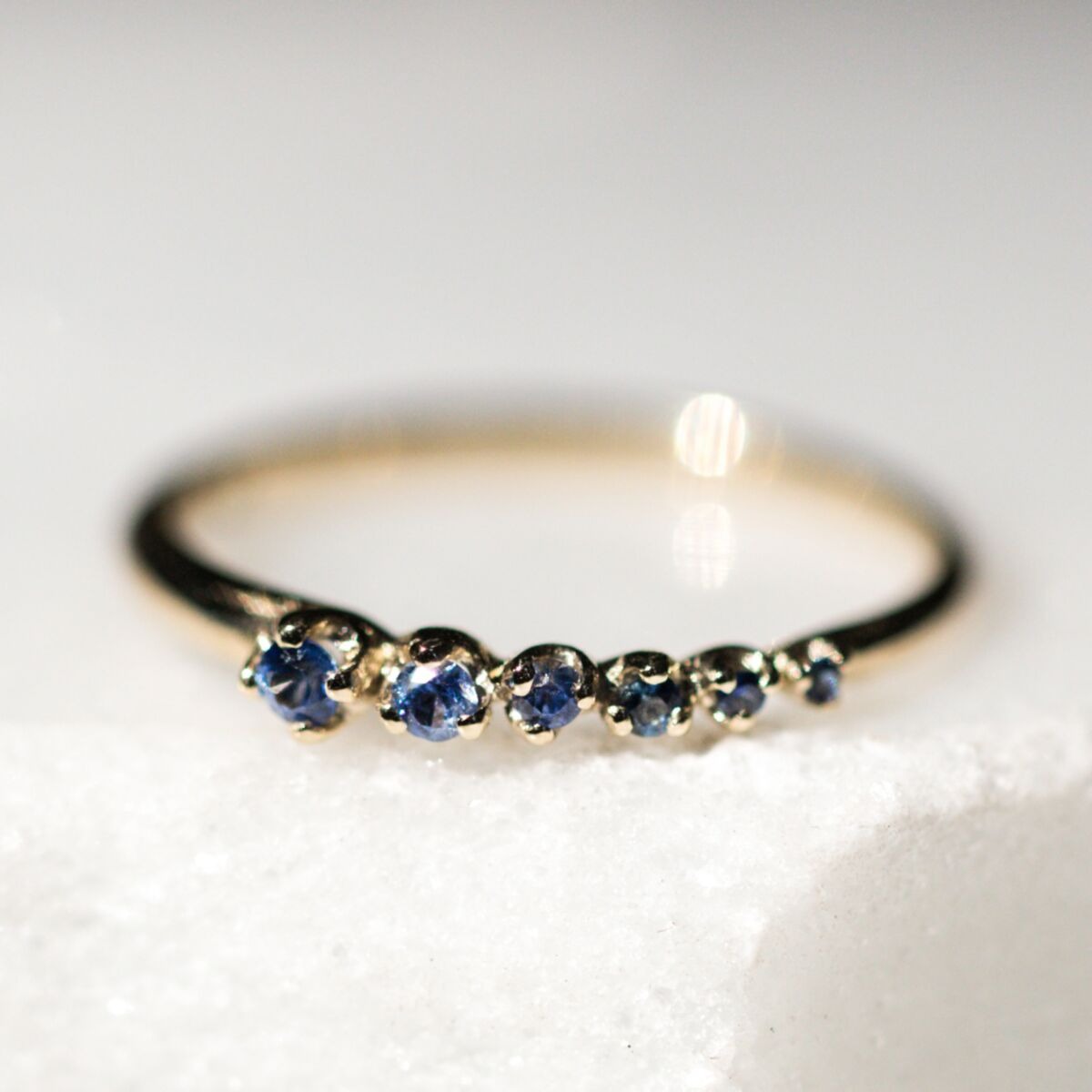 non diamond engagement ring with six small sapphires lined up from largest to smallest