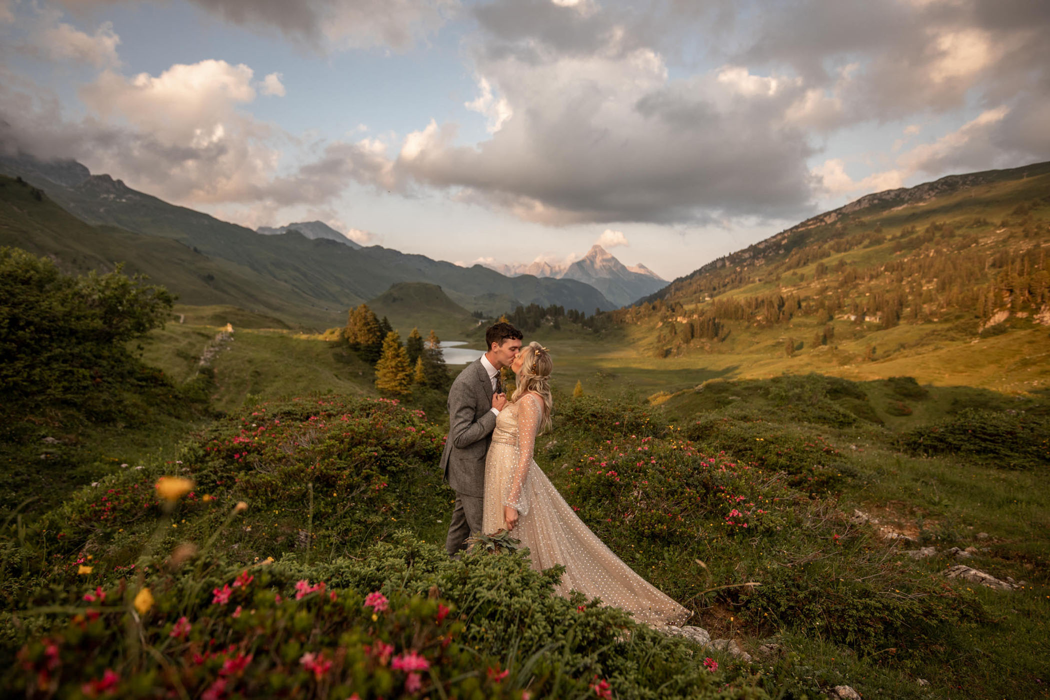 Bride and groom kissing in the Austrian Alps surrounded by wildflowers
