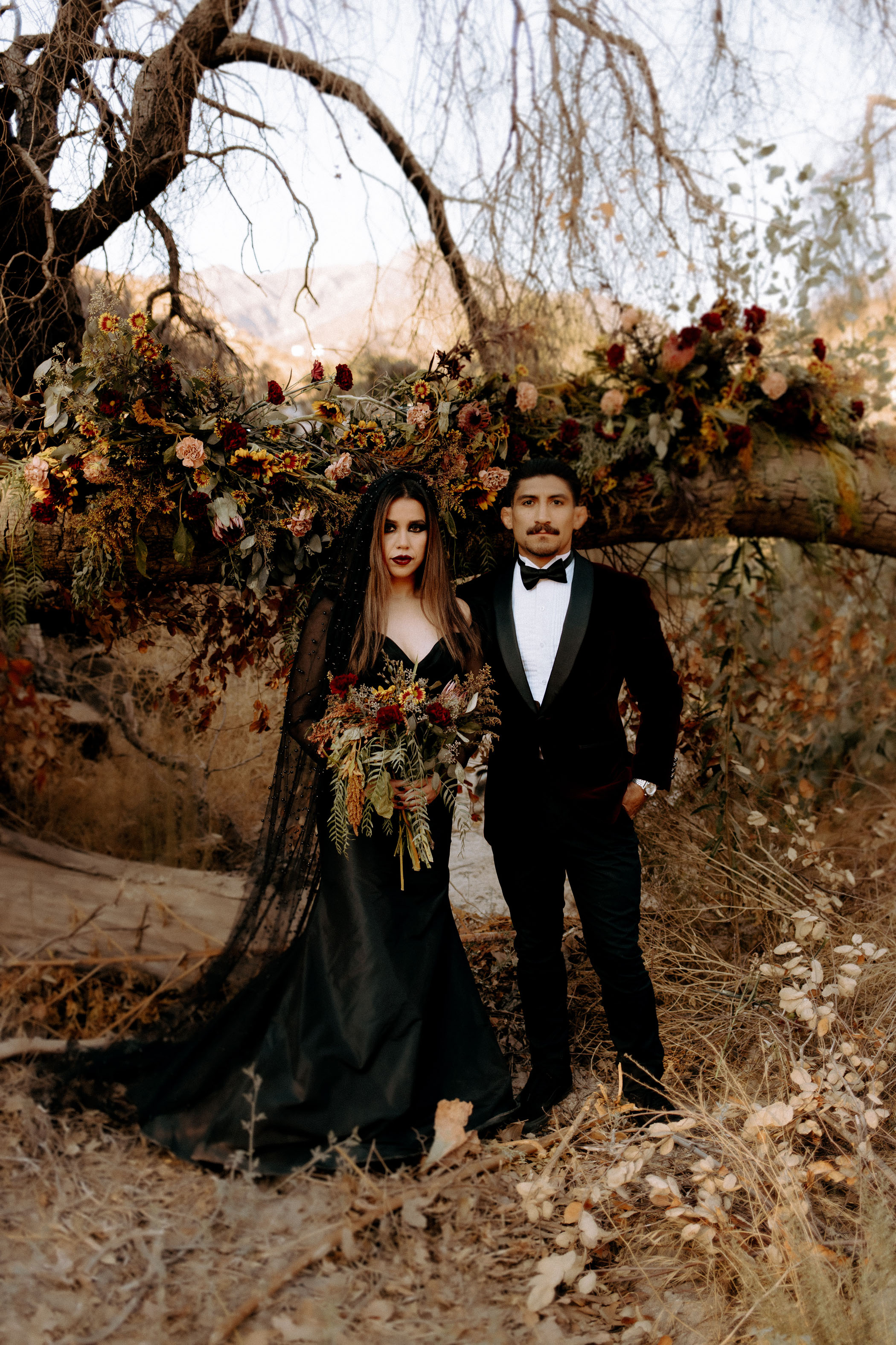 Bride in black wedding dress holding autumn flowers 