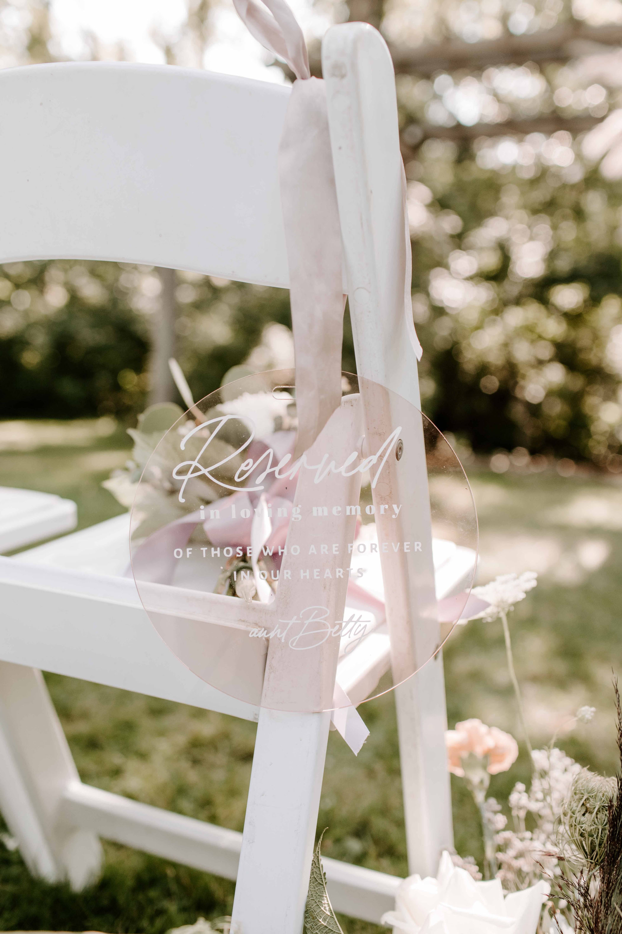 White wedding chair with a pink acrylic reservation note