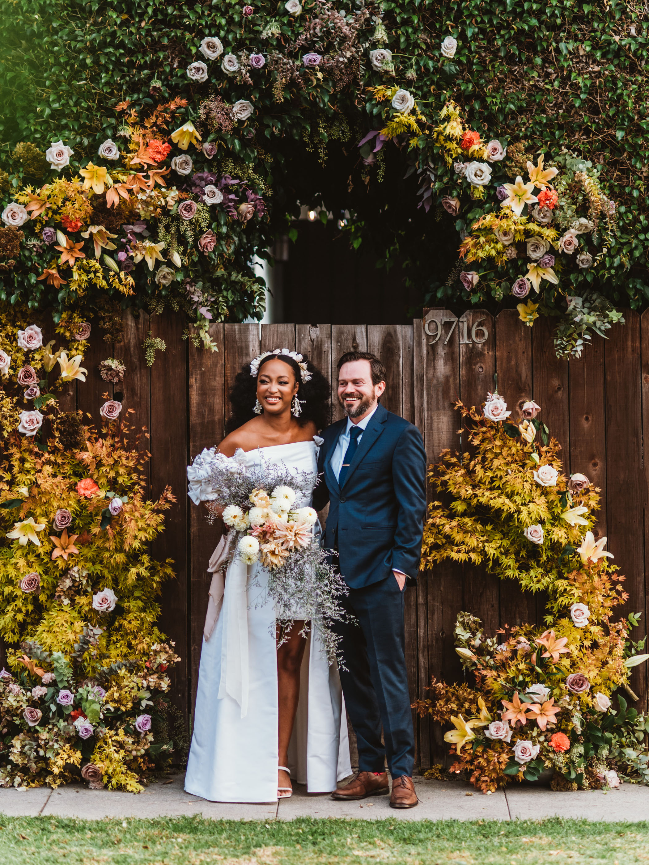 Bride and groom in front of floral backdrop