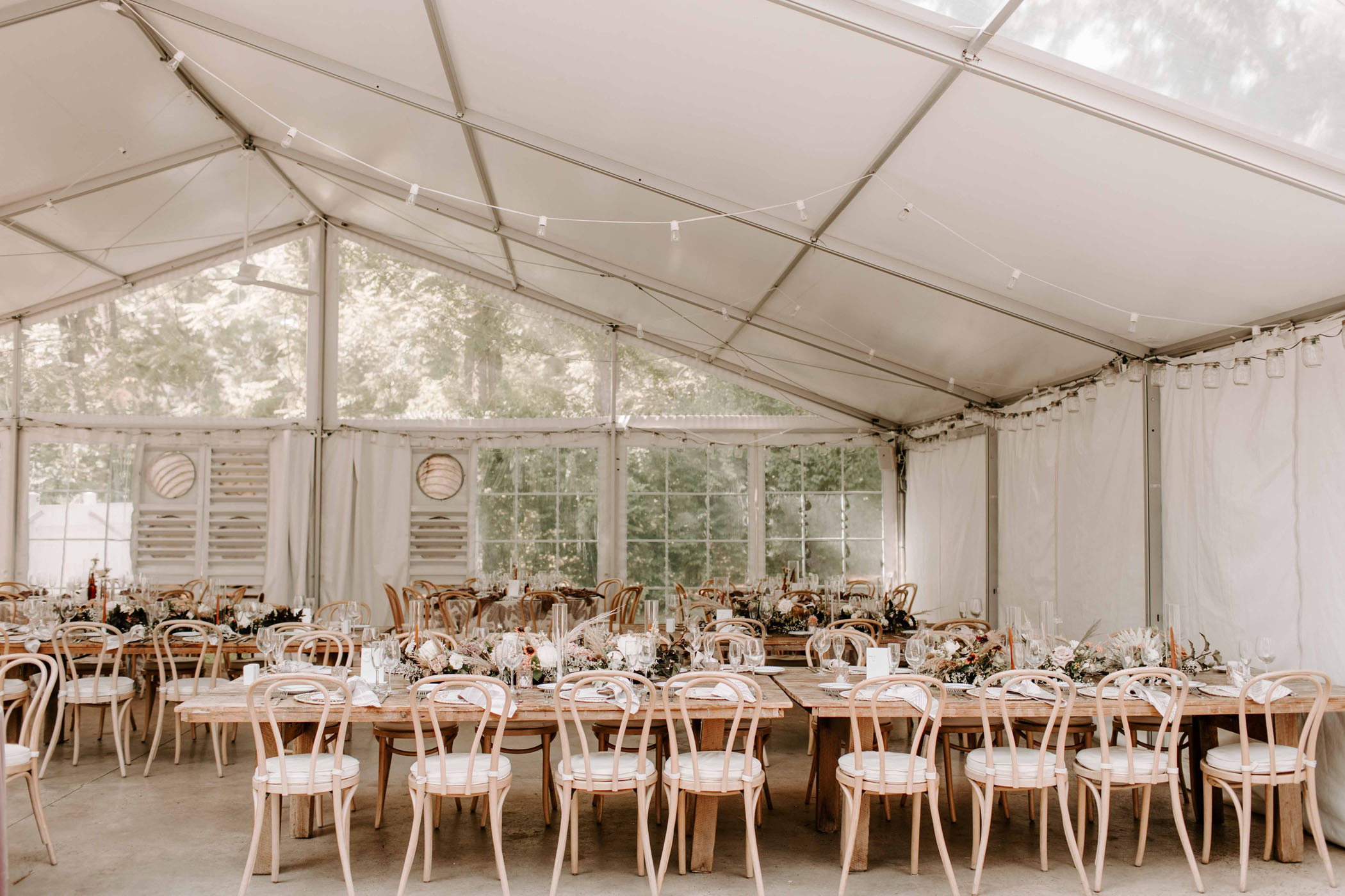 white wedding tent with pink chairs and wooden tables