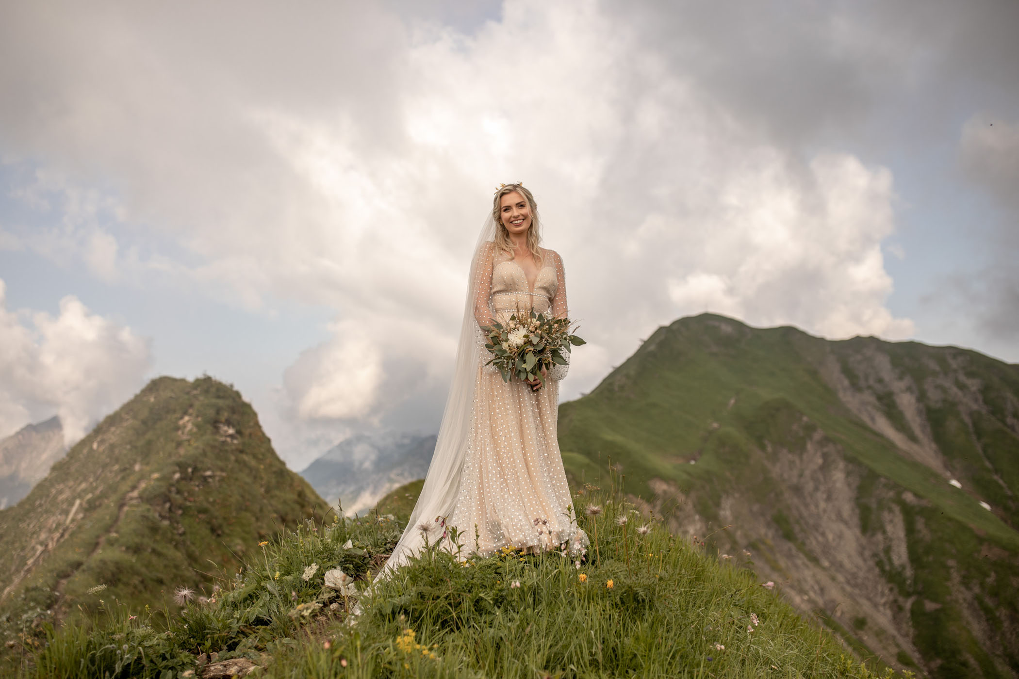 Bride in gold dress posing on a mountain on her wedding day