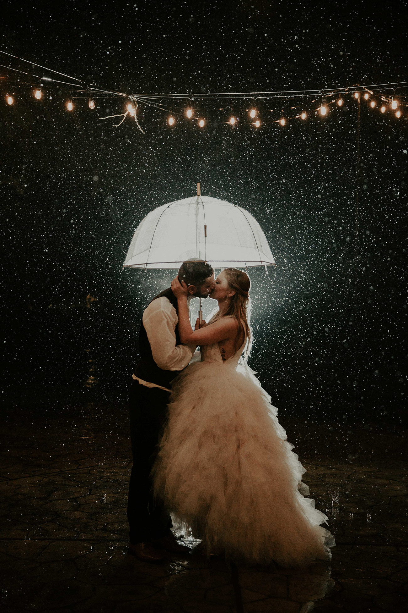 bride and groom with rain on wedding day and umbrella