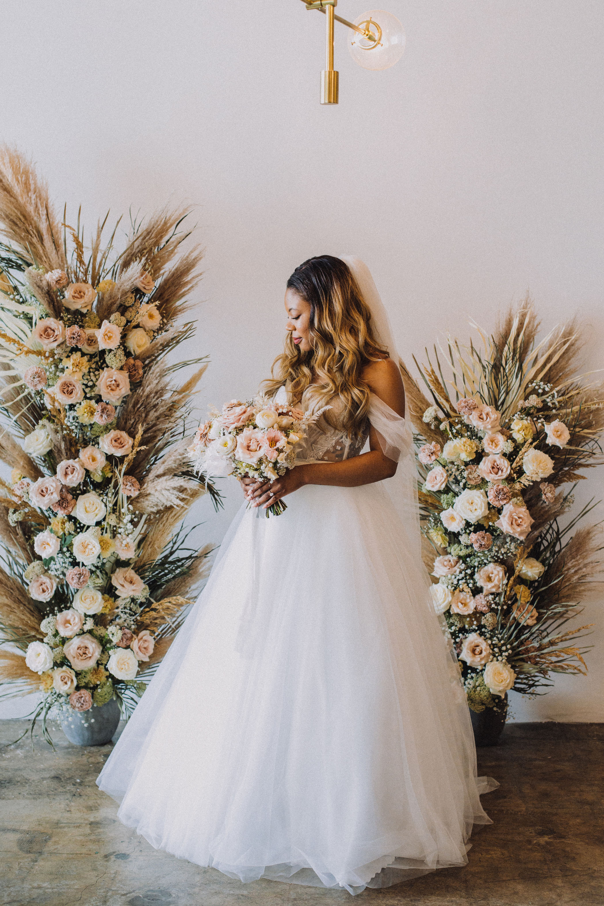 bride posing with pink and nude florals and pampas grass