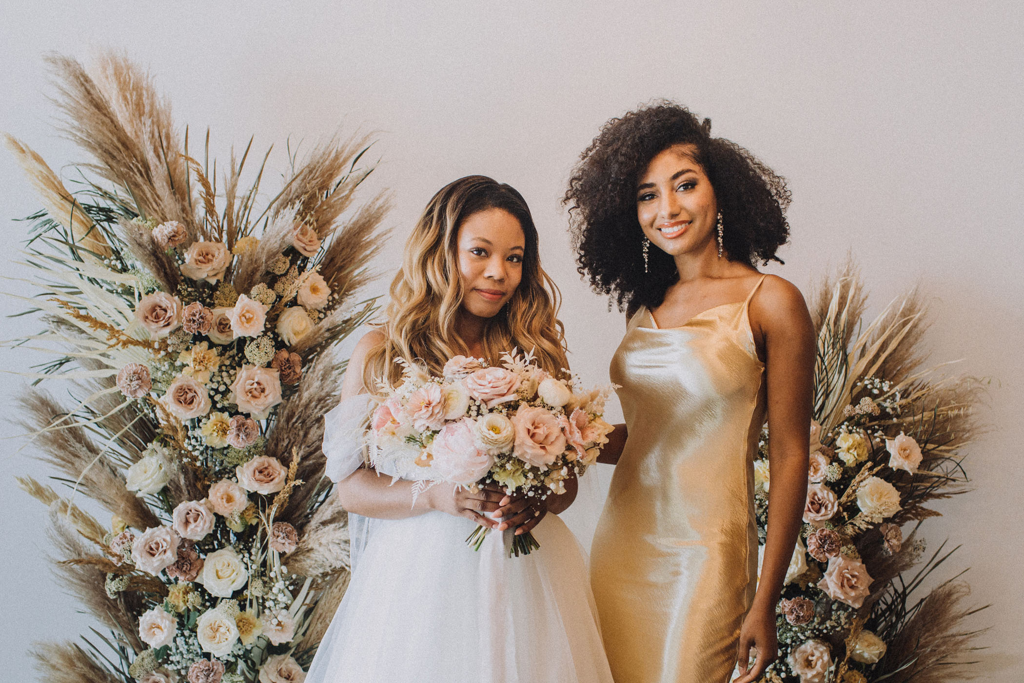 Bride posing next to her friend in a gold dress