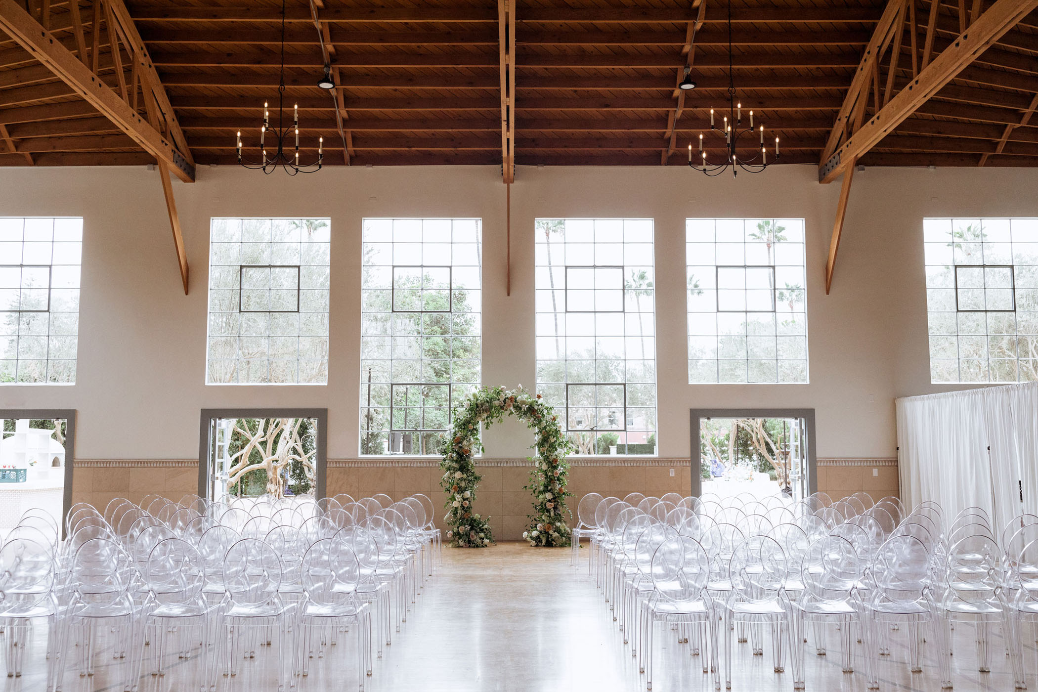wedding ceremony with ghost chairs and natural light from large windows