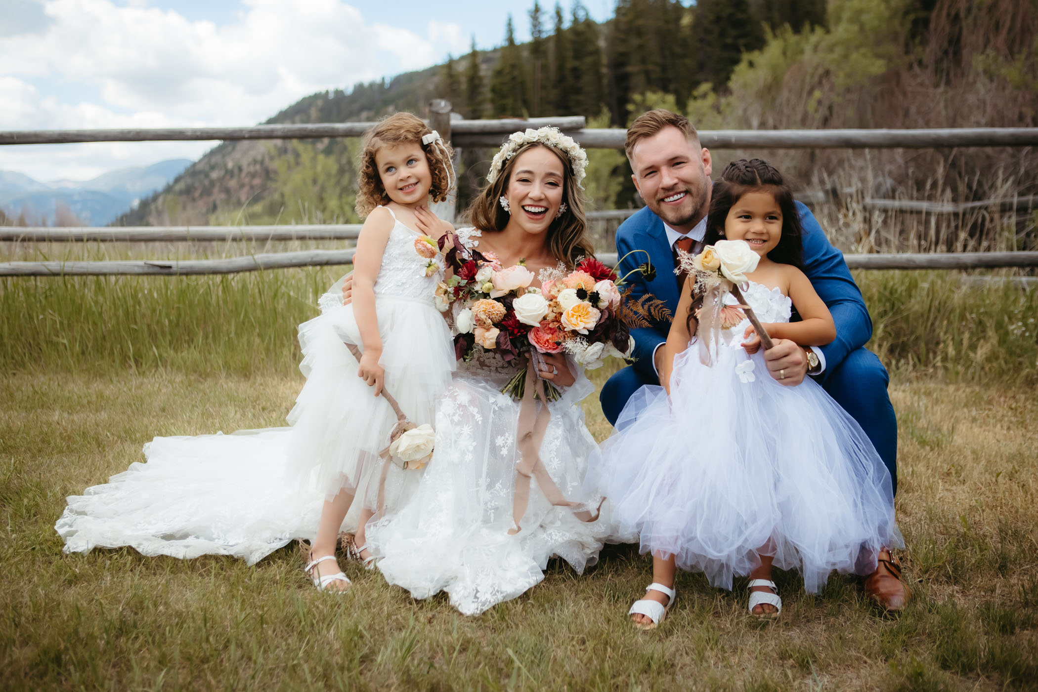 bride and groom smiling with flower girls