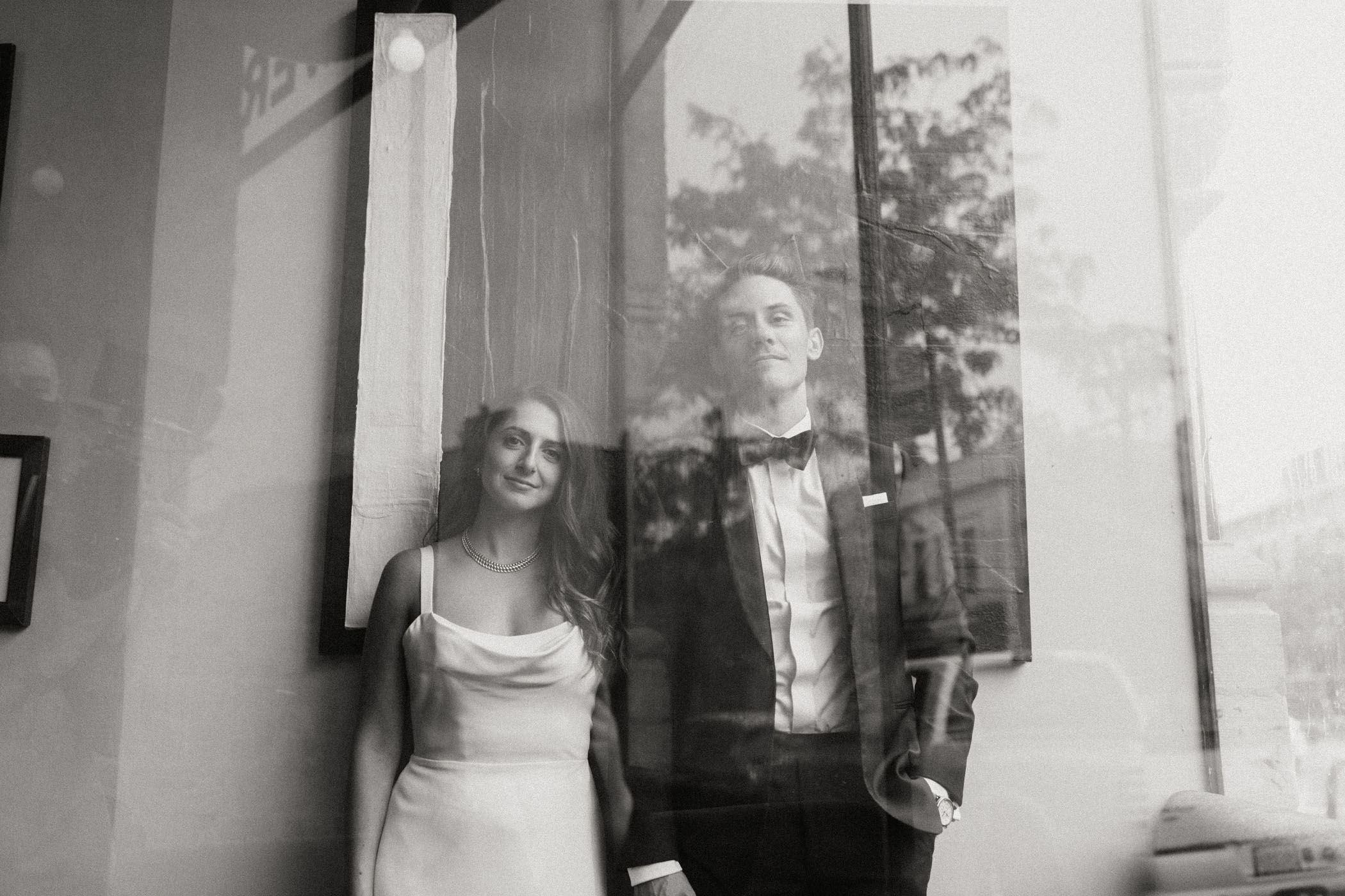 bride and groom smiling at camera through a window