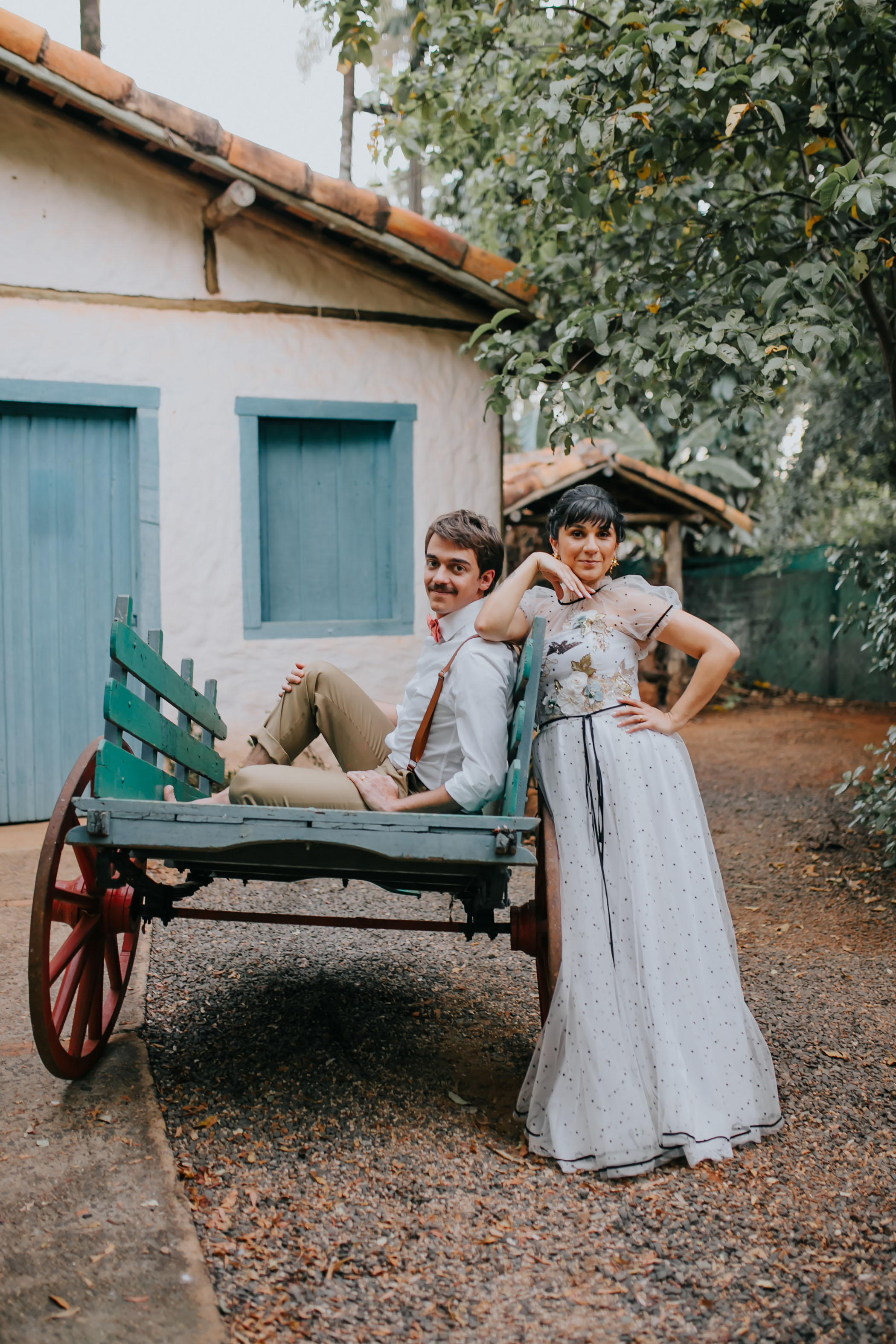 bride and groom posing in front of blue wheelbarrow
