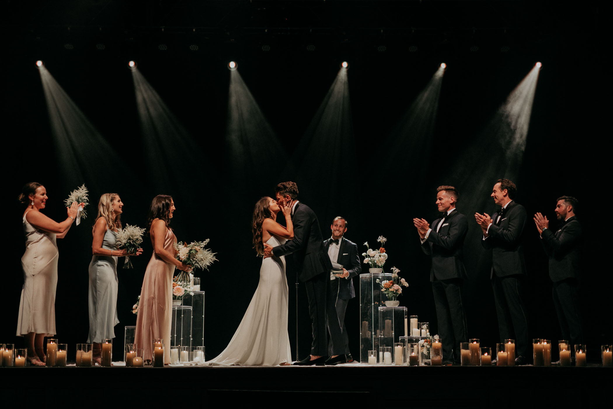 bride and groom kissing on music hall stage