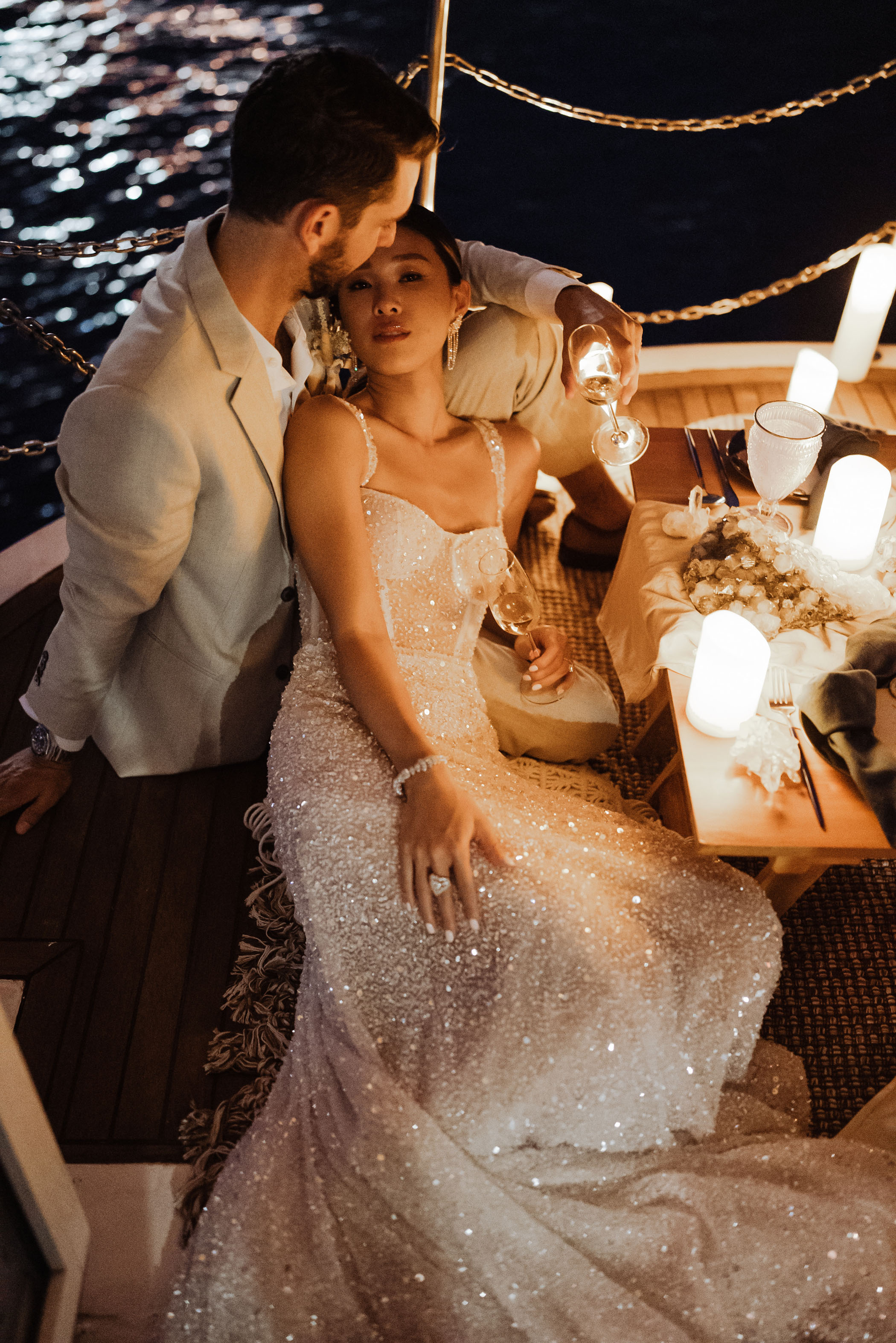 Bride and groom snuggling on boat at night