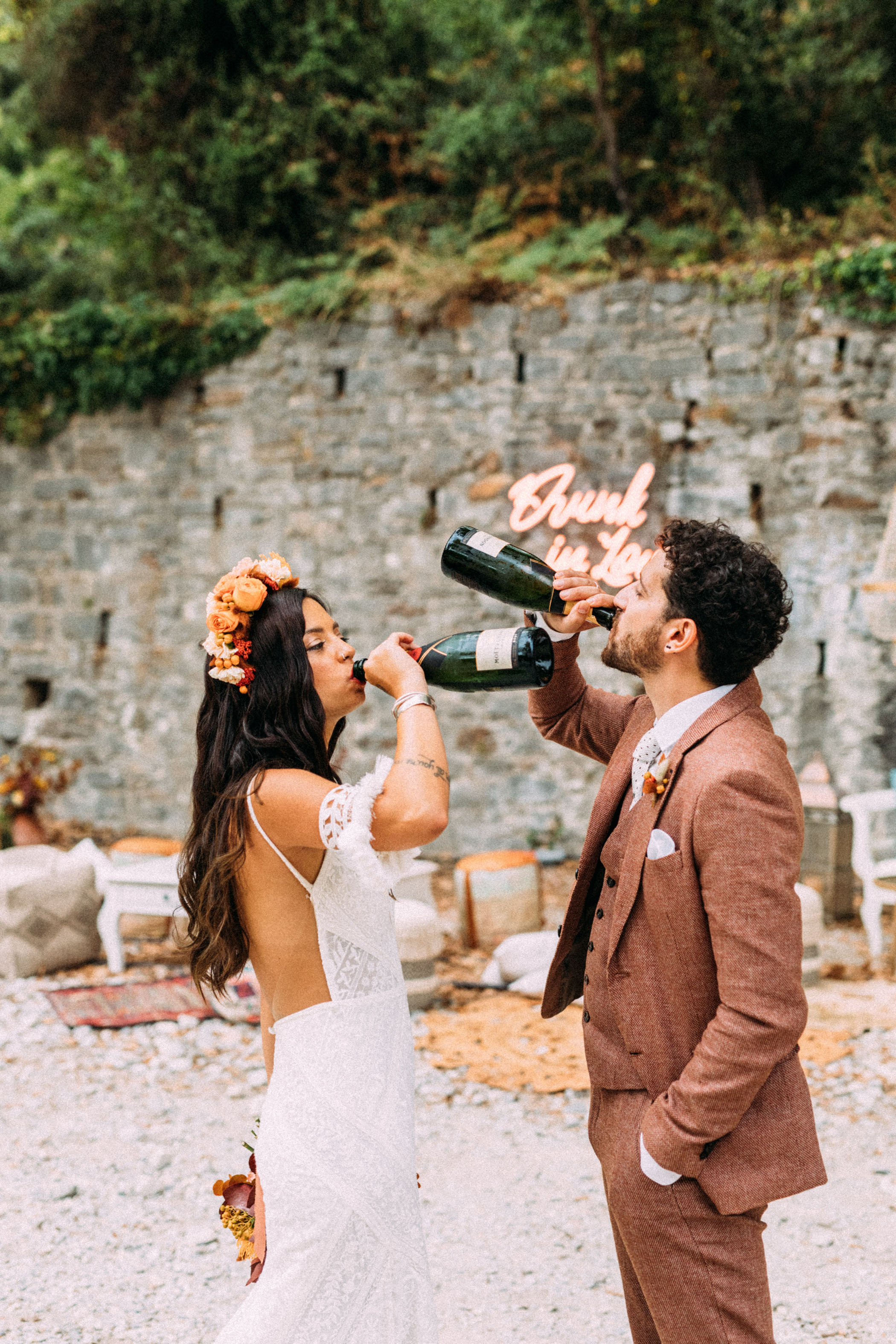 bride and groom drinking from bottles of champagne