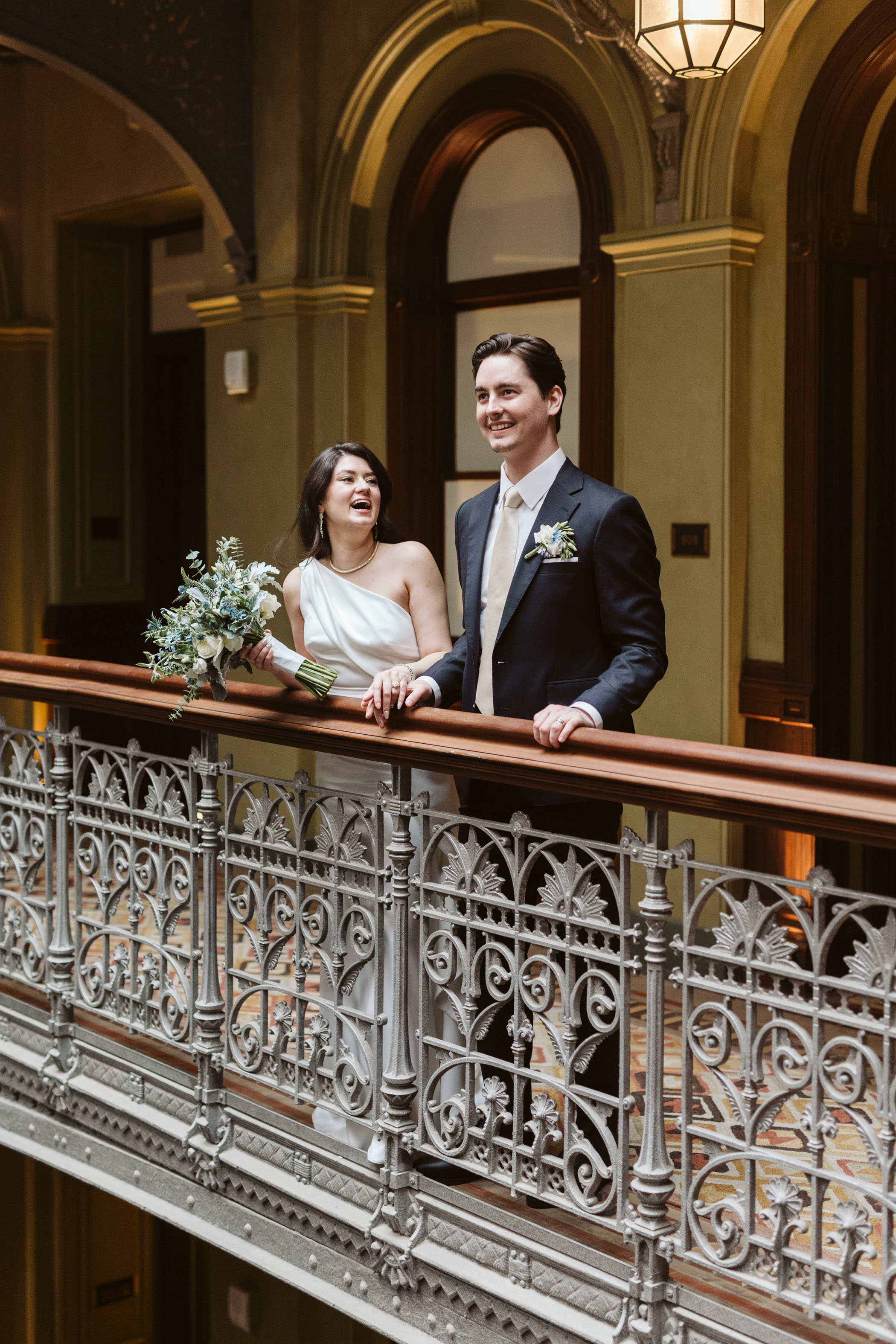 Bride and groom smiling over balcony 