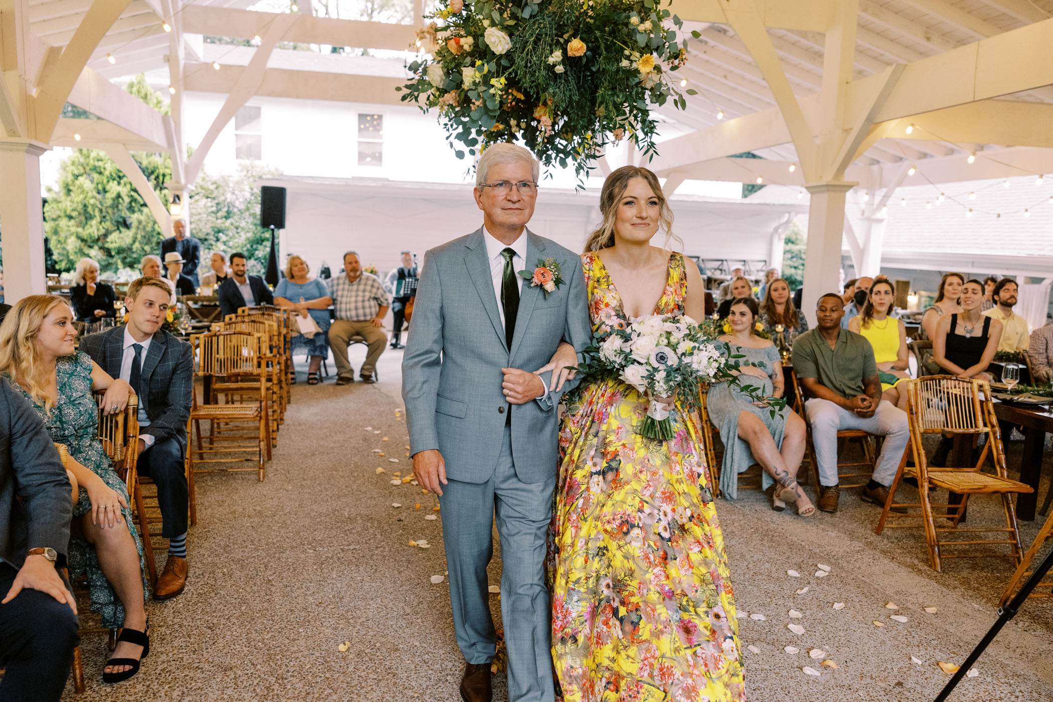 Bride in yellow floral wedding dress walking down the aisle 