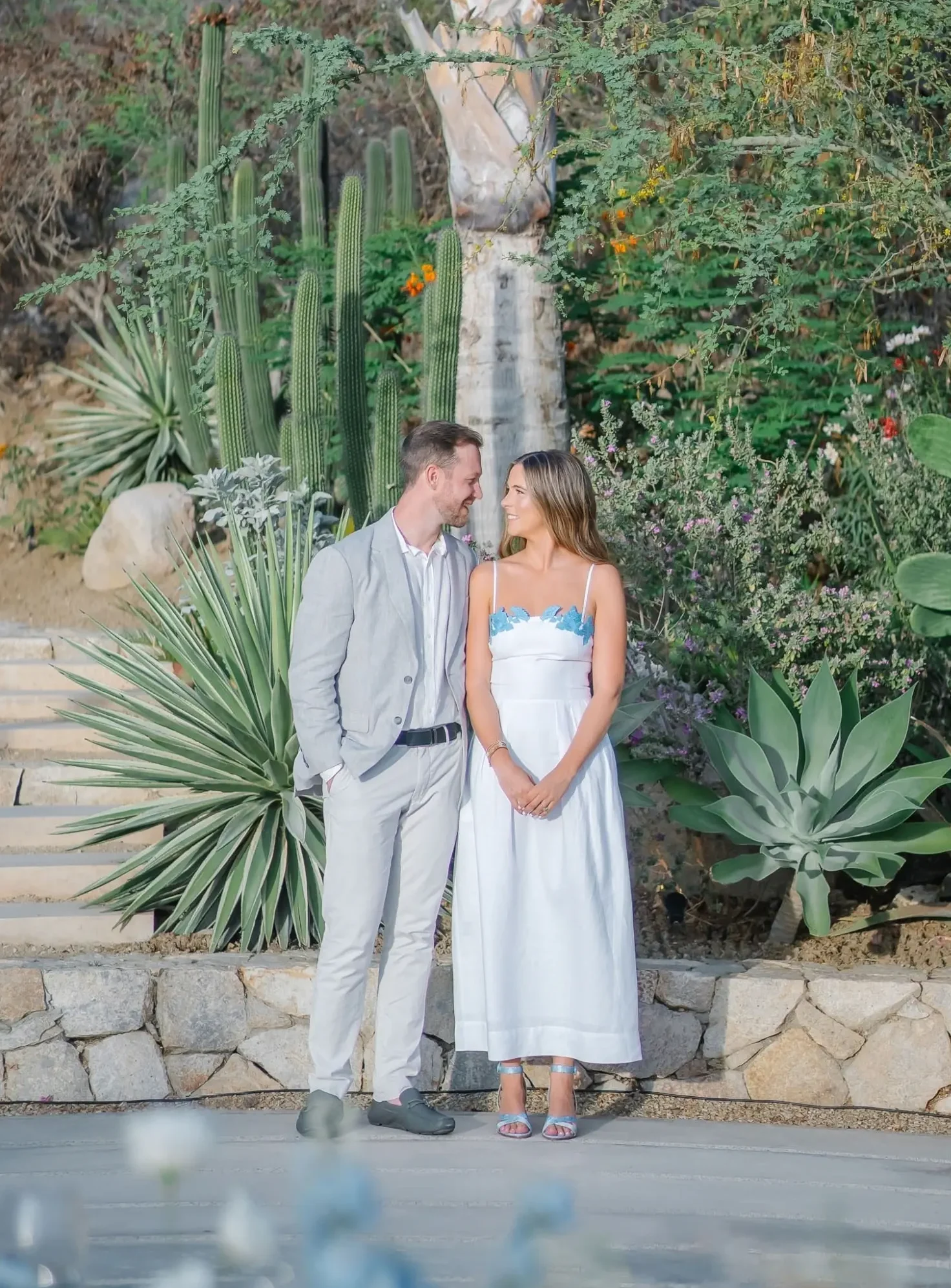 bride wearing cute outfit ideas including a blue and white midi dress and blue heels to her tropical outdoor rehearsal dinner