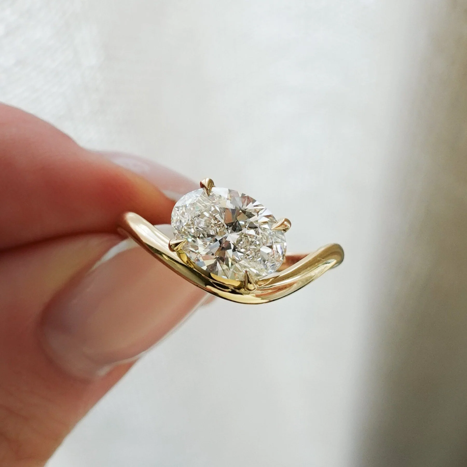 unique engagement rings featuring an east west oval diamond on a curved gold band